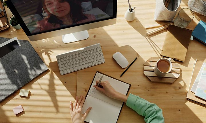 mulher sentada fazendo anotações na agenda sobre a mesa do escritório